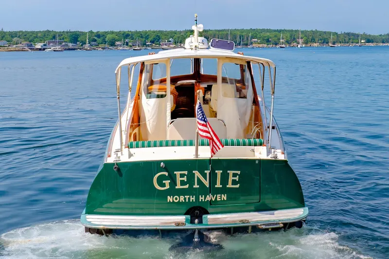 Slide: The Image of 1999 Hinckley Picnic Boat "Genie" on water, displaying American flag, North Haven backdrop. - 15