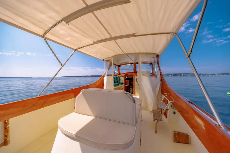 Slide: The Image of 1999 Hinckley Picnic Boat interior with canopy, overlooking calm blue waters. - 18