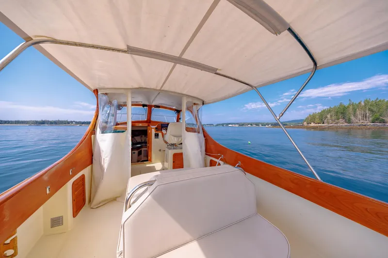 Slide: The Image of 1999 Hinckley Picnic Boat interior with canopy, cruising on calm waters under a clear blue sky. - 20