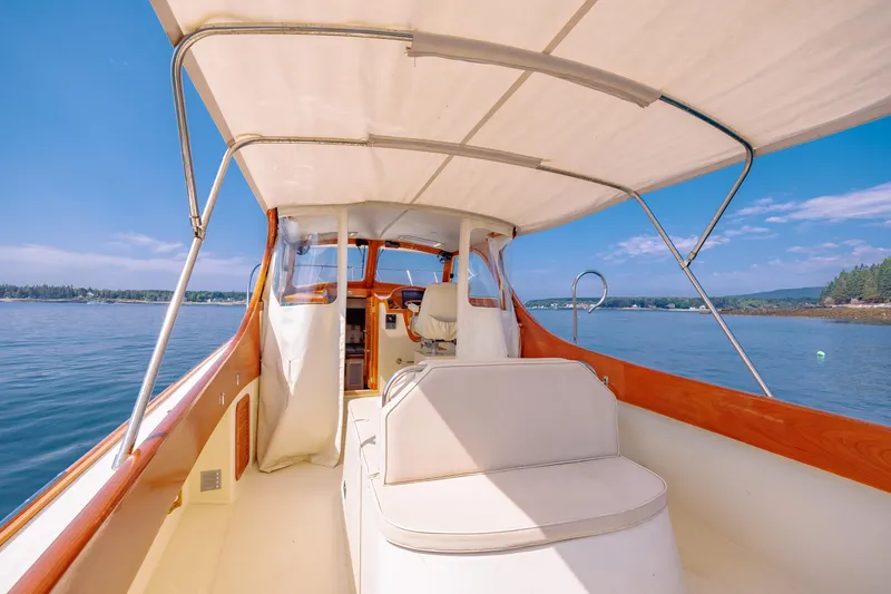 Slide: The Image of 1999 Hinckley Picnic Boat interior with canopy, cruising on calm waters under a clear blue sky. - 21