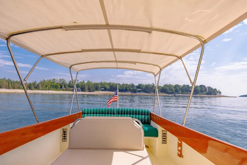 Slide: The Image of 1999 Hinckley Picnic Boat cruising on serene waters with canopy and American flag. - 22