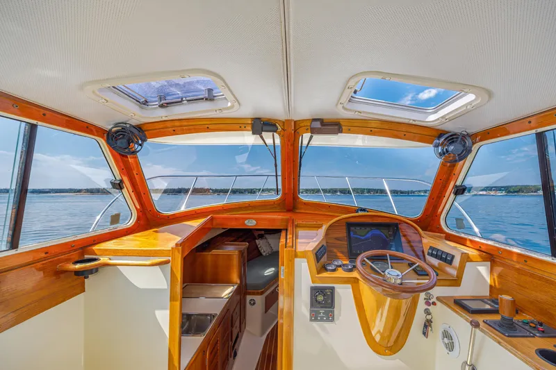 Slide: The Image of 1999 Hinckley Picnic Boat interior with wooden dashboard, steering wheel, and ocean view. - 26