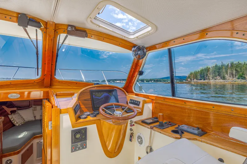 Slide: The Image of Interior view of a 1999 Hinckley Picnic Boat, showcasing wooden helm and scenic waterway. - 28