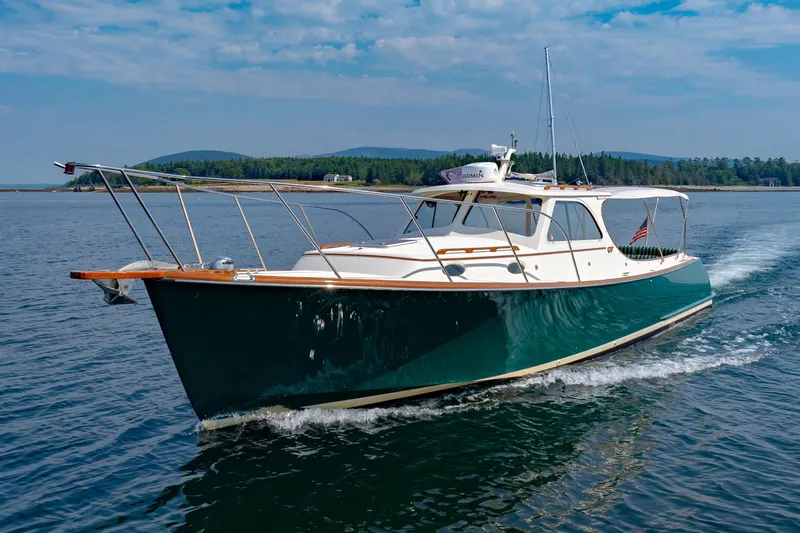Slide: The Image of 1999 Hinckley Picnic Boat cruising on a serene lake with scenic forested background. - 3