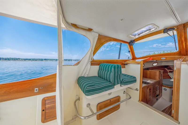 Slide: The Image of Interior of a 1999 Hinckley Picnic Boat with striped seating and scenic water view. - 31