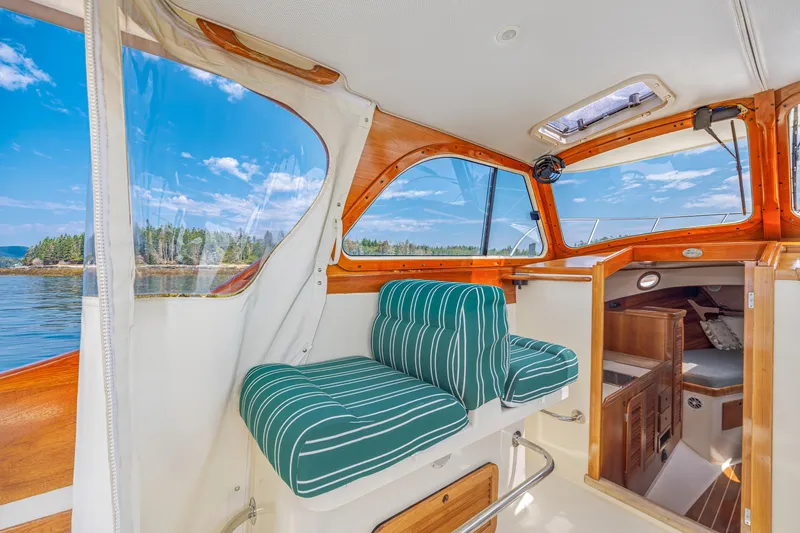 Slide: The Image of Interior of a 1999 Hinckley Picnic Boat with striped seating and scenic water view. - 32