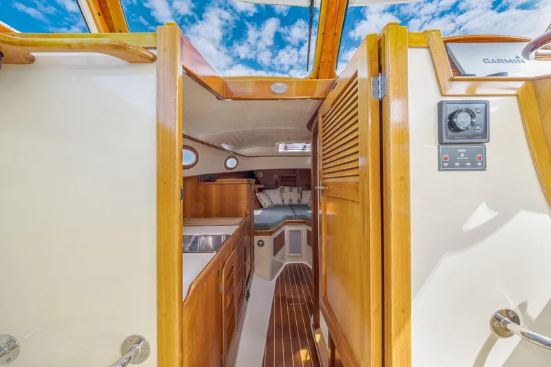 Slide: The Image of Interior view of a 1999 Hinckley Picnic Boat, featuring wooden cabinetry and cozy sleeping area. - 33