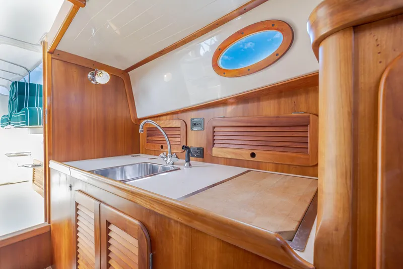 Slide: The Image of Interior of 1999 Hinckley Picnic Boat with wooden cabinetry and stainless steel sink. - 34