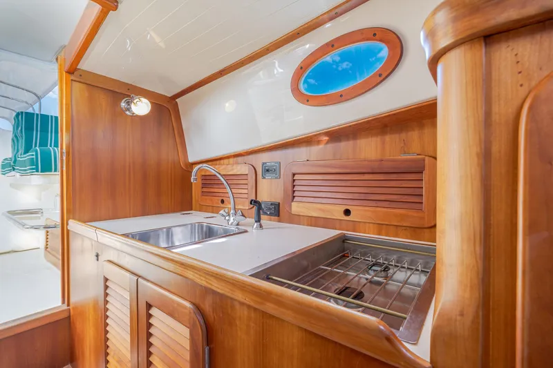 Slide: The Image of 1999 Hinckley Picnic Boat interior with wooden cabinetry and compact kitchen area. - 35