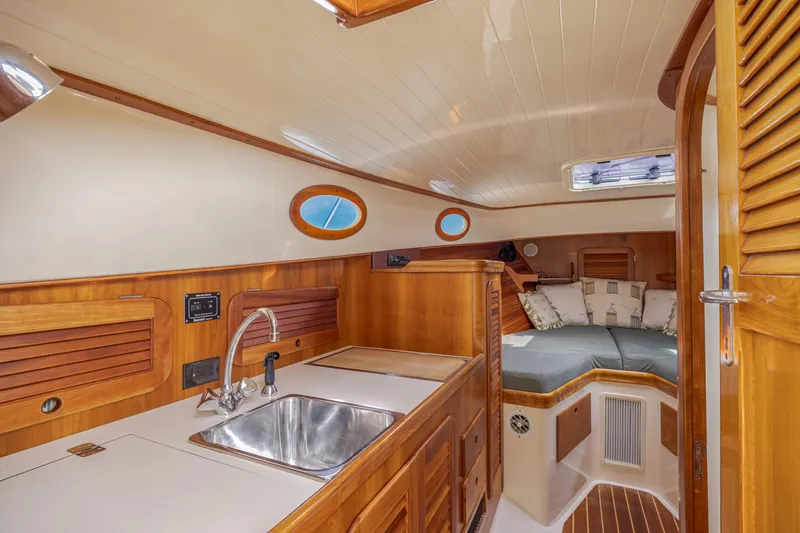 Slide: The Image of 1999 Hinckley Picnic Boat interior with wood finish, kitchenette, and cozy seating area. - 36