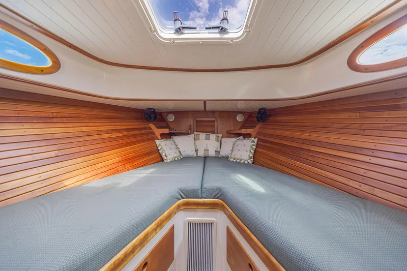 Slide: The Image of 1999 Hinckley Picnic Boat interior with wooden paneling and cozy bedding. - 38