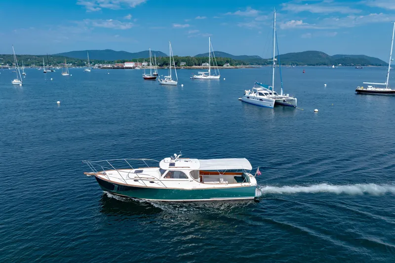 Slide: The Image of 1999 Hinckley Picnic Boat cruising in a scenic harbor with sailboats and mountains. - 43