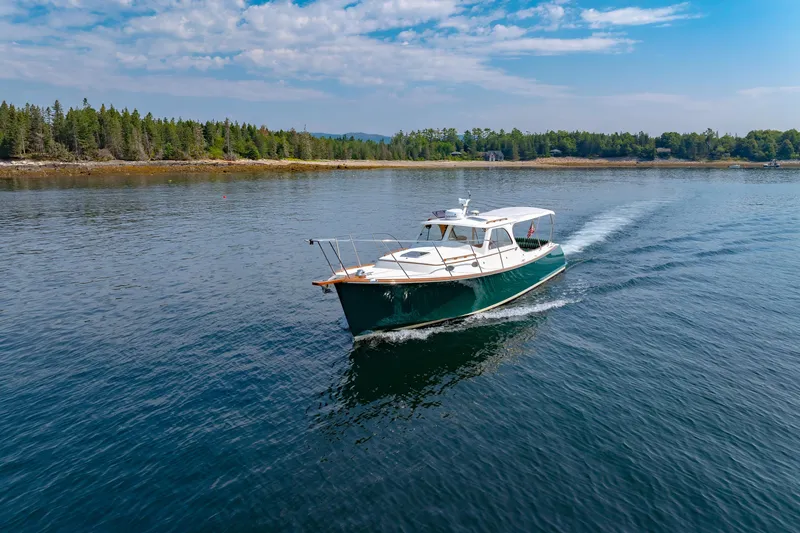 Slide: The Image of 1999 Hinckley Picnic Boat cruising on a serene lake with forested shoreline. - 5