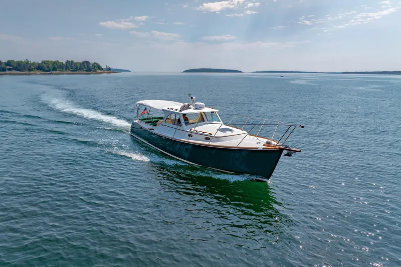 Slide: The Image of 1999 Hinckley Picnic Boat cruising on a serene lake under a clear sky. - 6
