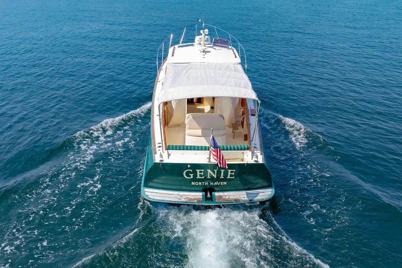 Slide: The Image of 1999 Hinckley Picnic Boat cruising on open water, rear view with American flag. - 8