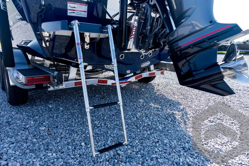 Slide: The Image of 2026 Pathfinder 2200 TRS boat with ladder and trailer on gravel surface. - 23