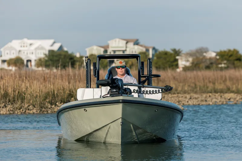 Slide: The Image of Man piloting a 2025 Vtech 18 boat on a calm waterway near coastal homes. - 8