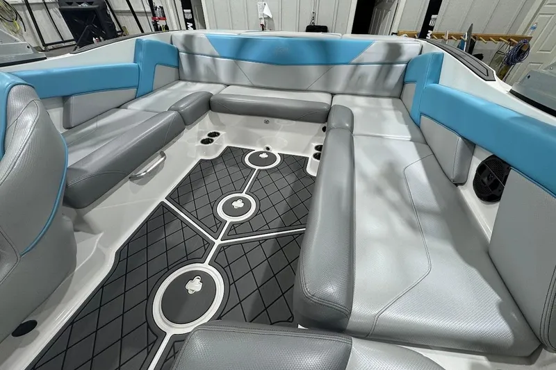 Slide: The Image of 2019 MasterCraft NXT22 interior seating with gray and blue upholstery, featuring cup holders. - 13