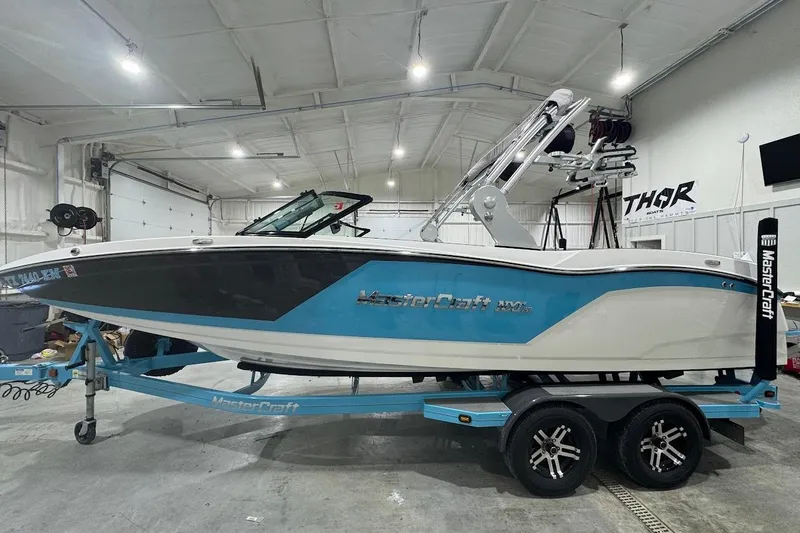Slide: The Image of 2019 MasterCraft NXT22 boat in a garage, featuring a sleek blue and white design. - 2