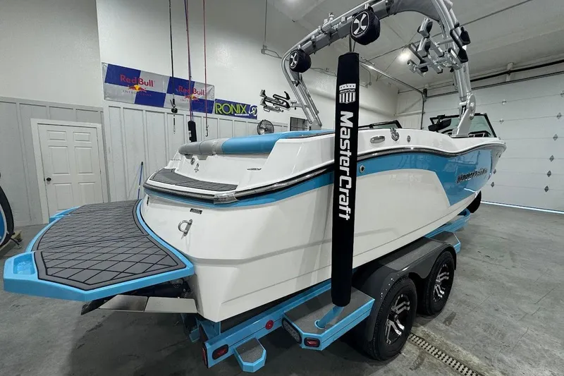 Slide: The Image of 2019 MasterCraft NXT22 boat in garage, featuring blue and white design on trailer. - 6