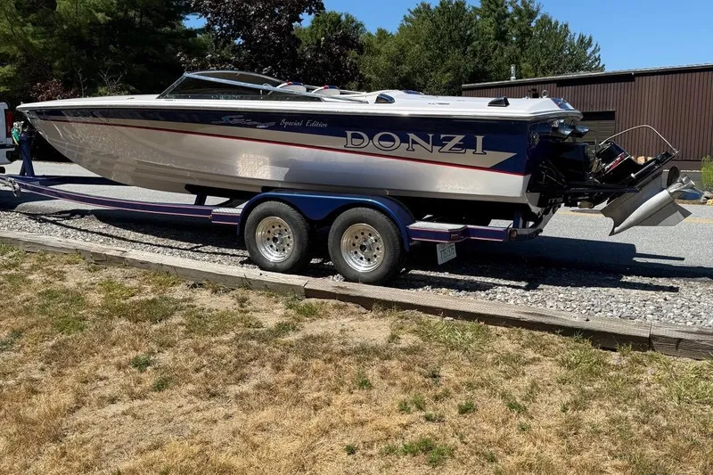 Slide: The Image of 2002 Donzi 22 Classic boat on trailer, parked outdoors, showcasing sleek design and vibrant colors. - 12