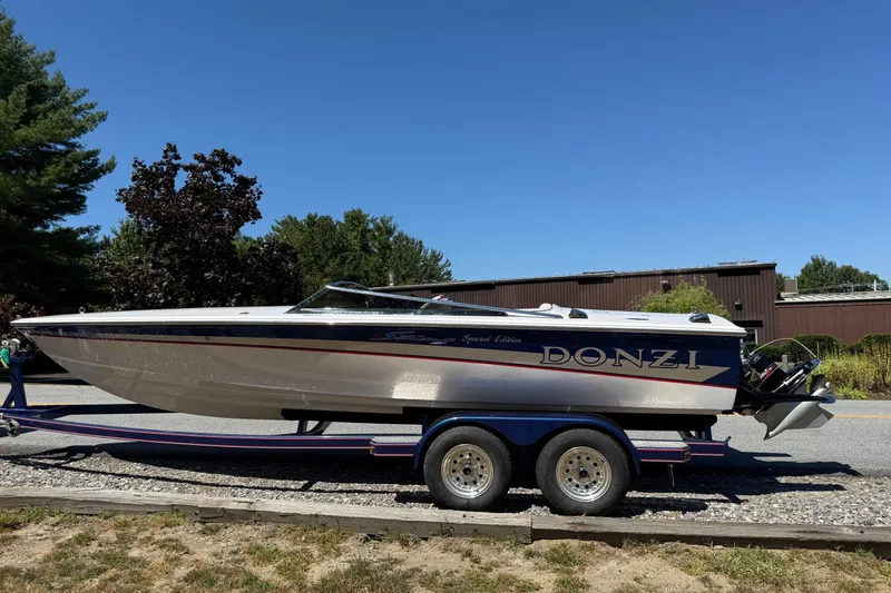 Slide: The Image of 2002 Donzi 22 Classic boat on trailer, parked outdoors under clear blue sky. - 13