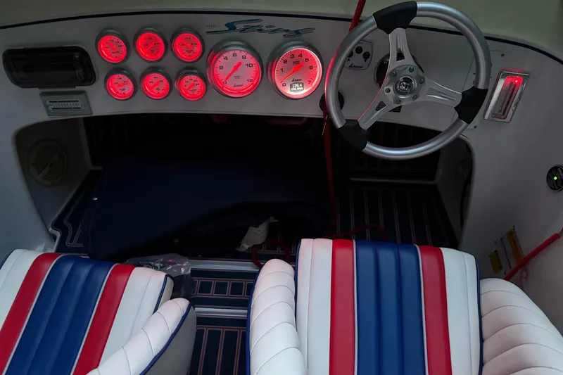 Slide: The Image of 2002 Donzi 22 Classic boat interior with red gauges and striped seats. - 3
