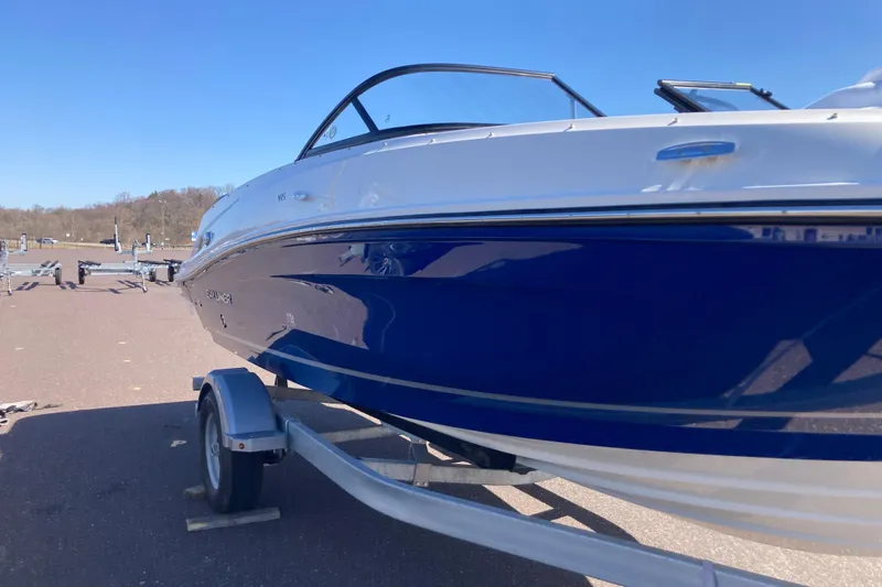 Slide: The Image of 2025 Bayliner VR5 Bowrider I/O on trailer, blue and white exterior, sunny day. - 2