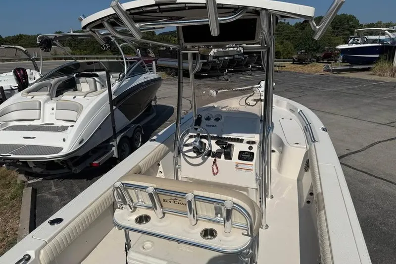 Slide: The Image of 2018 Carolina Skiff 23LX boat interior with steering console and seating, parked outdoors. - 10