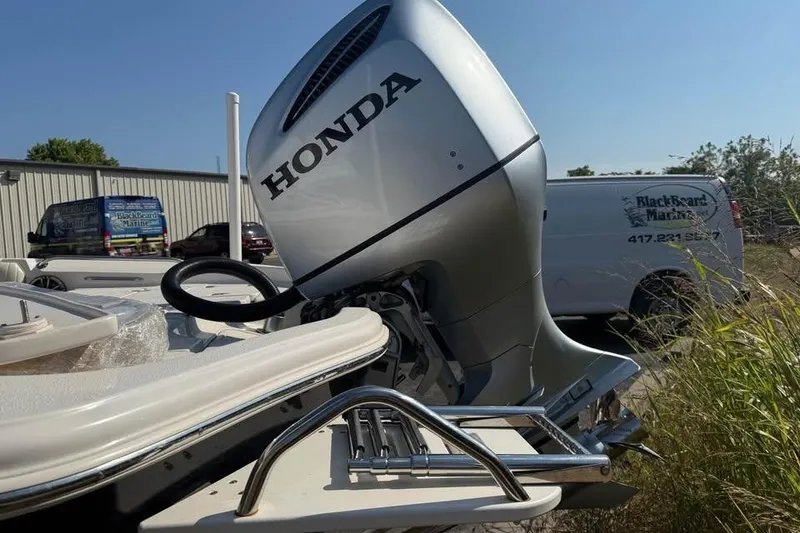 Slide: The Image of 2018 Carolina Skiff 23LX with Honda outboard motor, parked near a marine service van. - 6