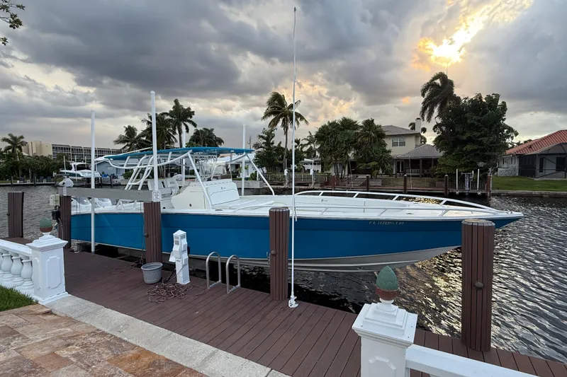 The Image of 2021 Marlin 39 CC boat docked by waterfront homes under cloudy sky. - 1