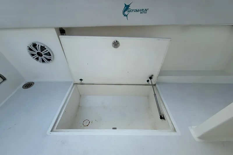 Slide: The Image of Open storage compartment on 2021 Marlin 39 CC boat deck, featuring a speaker and drain. - 19