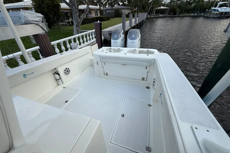 Slide: The Image of 2021 Marlin 39 CC boat deck with dual Suzuki engines docked by waterfront. - 21