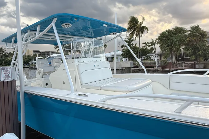 Slide: The Image of 2021 Marlin 39 CC boat with blue canopy, docked near palm trees under cloudy sky. - 4