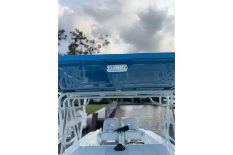 Slide: The Image of 2021 Marlin 39 CC boat with blue canopy, docked under cloudy sky. - 60