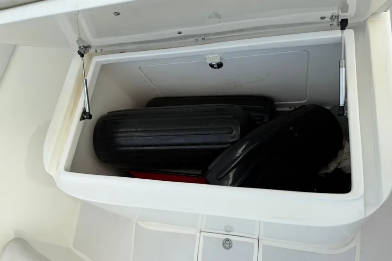 Slide: The Image of Open storage compartment on 2021 Marlin 39 CC boat, containing black fenders. - 81