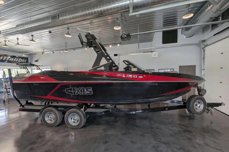 The Image of 2018 Axis T23 boat in showroom, black and red design on trailer. - 7