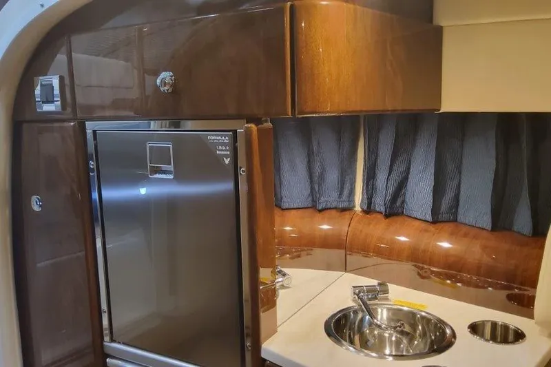 Slide: The Image of 2024 Formula 310 Sun Sport interior with kitchenette, featuring wood cabinetry and stainless steel sink. - 40