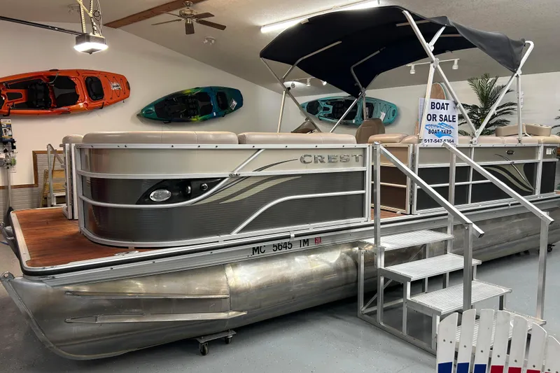 Slide: The Image of 2013 Crest Classic 230 pontoon boat for sale in showroom with kayaks displayed. - 1