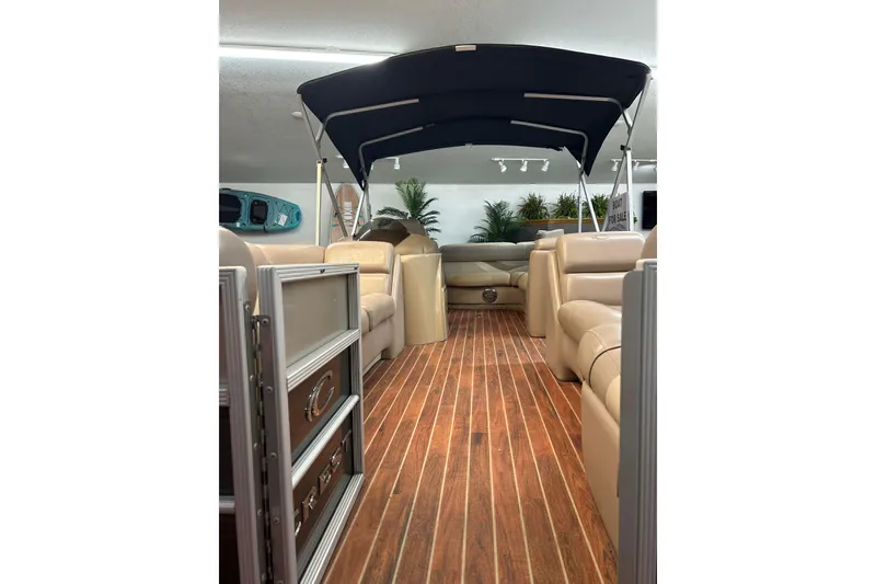 Slide: The Image of 2013 Crest Classic 230 pontoon boat interior with wood flooring and beige seating. - 3