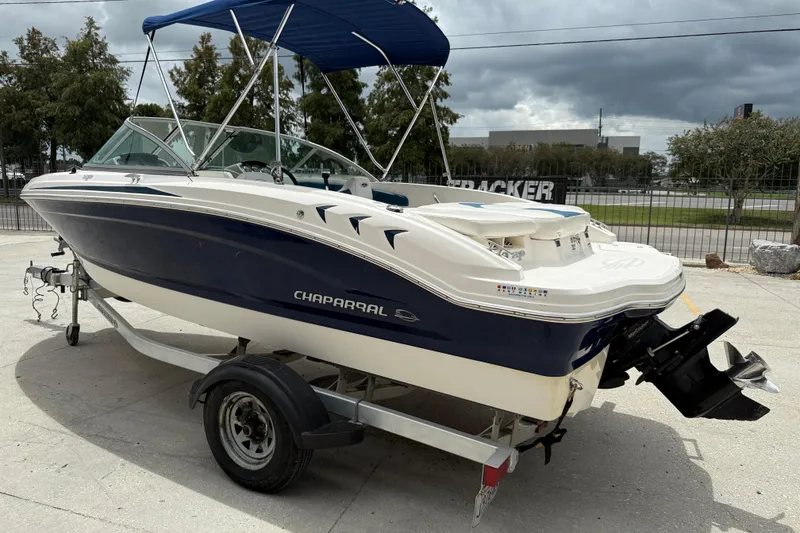Slide: The Image of 2016 Chaparral 19 H2O Sport boat with blue and white exterior on a trailer. - 4