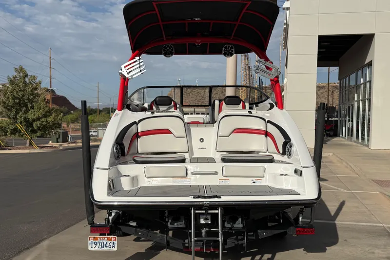 Slide: The Image of 2019 Yamaha Boats 242X E-Series, rear view, parked outdoors near a building. - 13