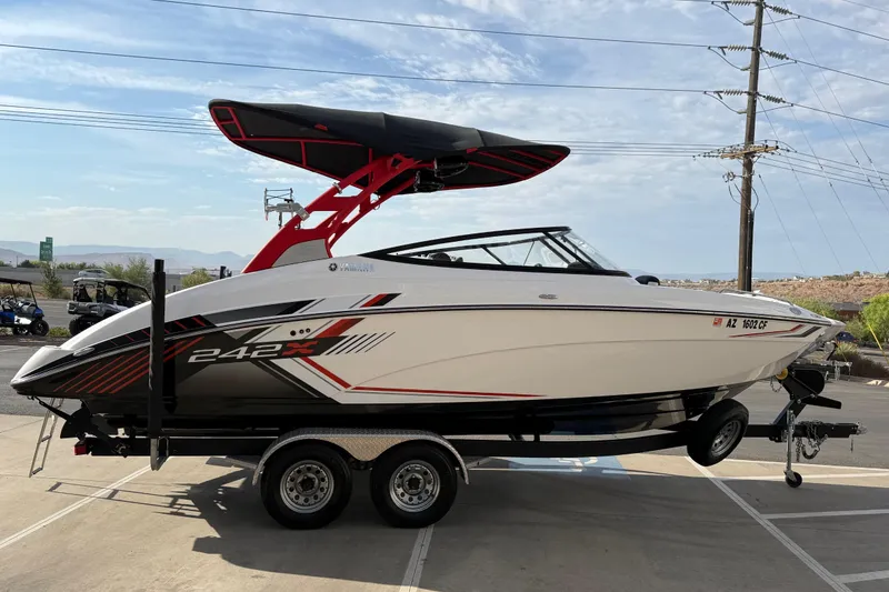 Slide: The Image of 2019 Yamaha Boats 242X E-Series on trailer, sleek design, vibrant graphics, outdoor setting. - 16