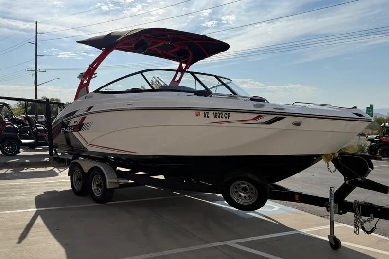 Slide: The Image of 2019 Yamaha Boats 242X E-Series on trailer, parked outdoors under a clear sky. - 18