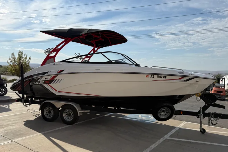 Slide: The Image of 2019 Yamaha Boats 242X E-Series on trailer, sleek design, red accents, parked outdoors. - 19