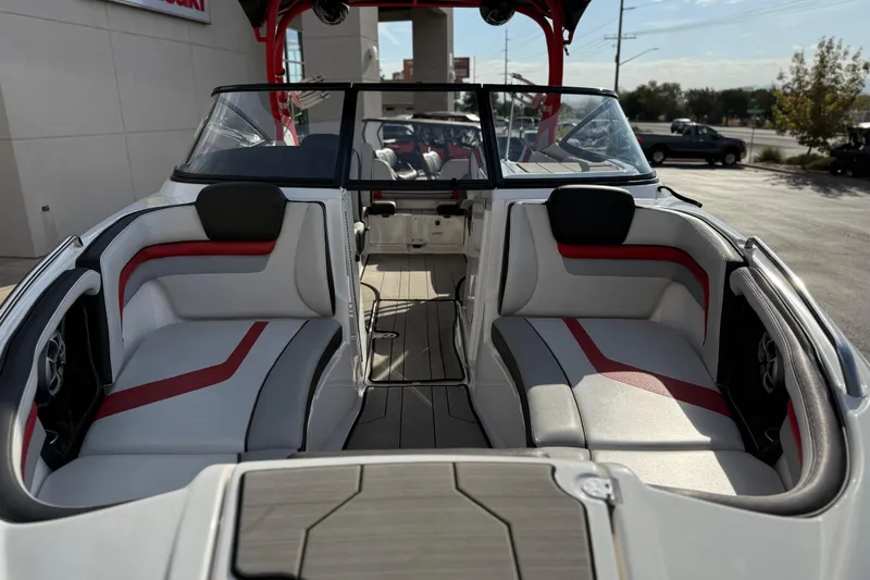 Slide: The Image of 2019 Yamaha Boats 242X E-Series interior with red and gray seating, docked outdoors. - 26