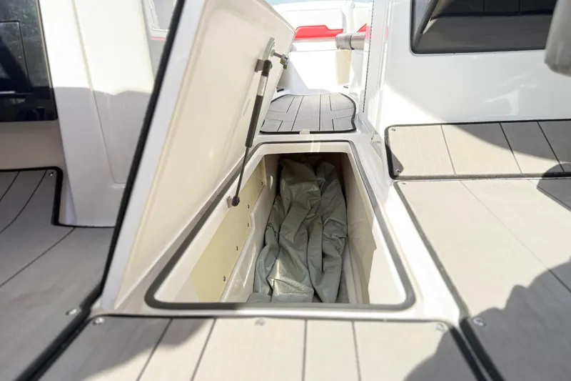 Slide: The Image of 2019 Yamaha Boats 242X E-Series storage compartment with open hatch, showcasing interior space. - 56