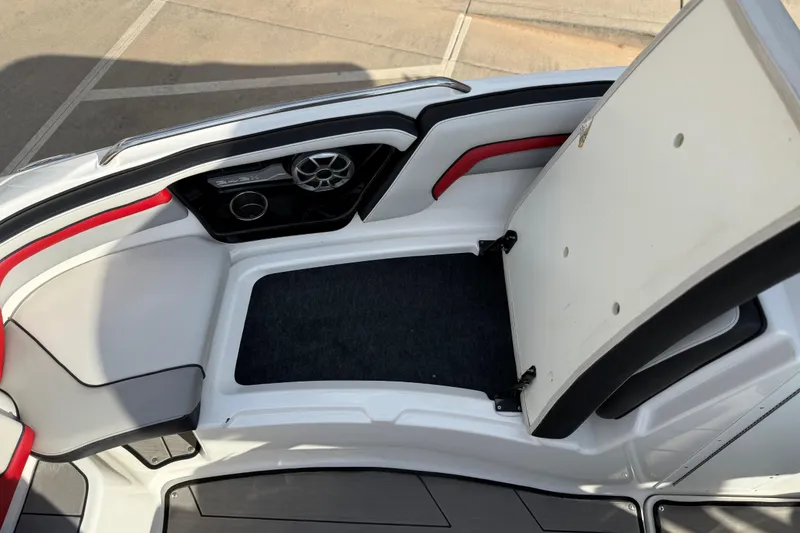 Slide: The Image of 2019 Yamaha Boats 242X E-Series interior with open storage compartment and speaker. - 63