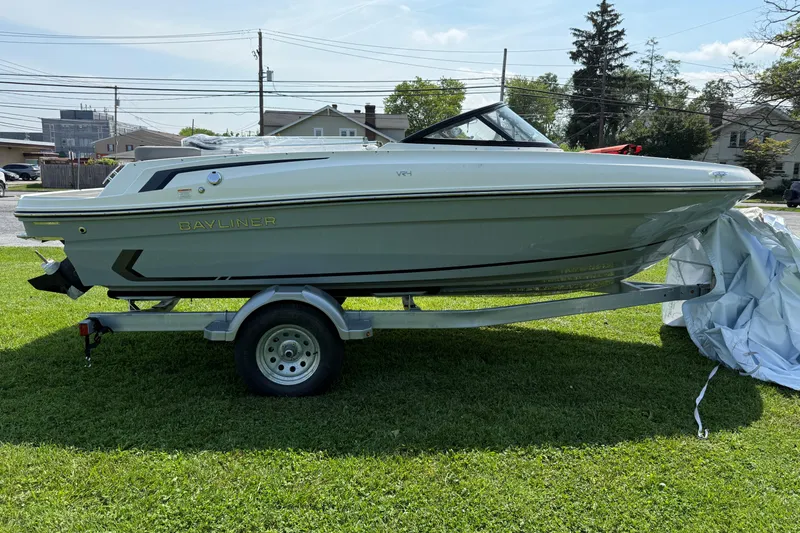 Slide: The Image of 2025 Bayliner VR4 Bowrider I/O on trailer, parked on grass, side view. - 2
