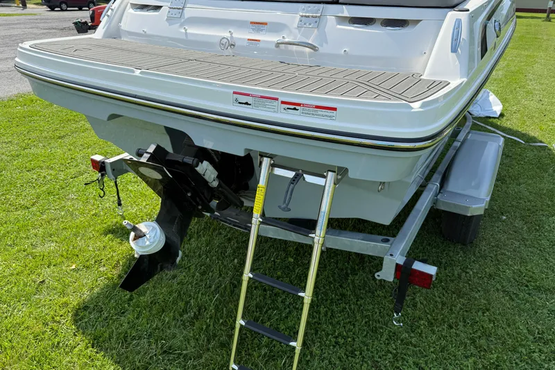 Slide: The Image of 2025 Bayliner VR4 Bowrider I/O on trailer, rear view with ladder, parked on grass. - 4